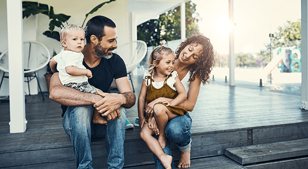 A family of four sitting on the steps of their home stock photo